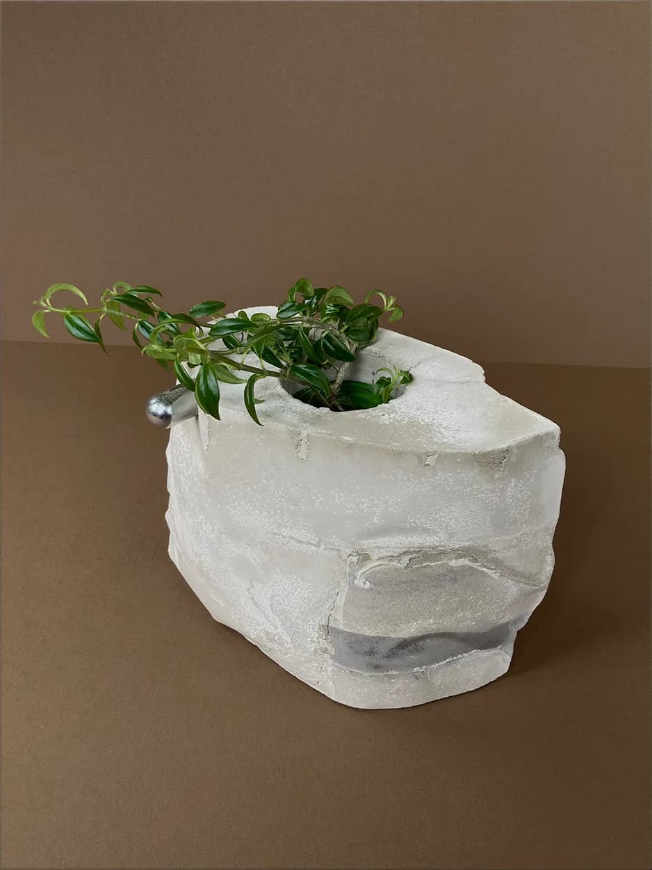 MOTHER — an irregular concrete vessel with a single hardware knob, planted with a trailing vine